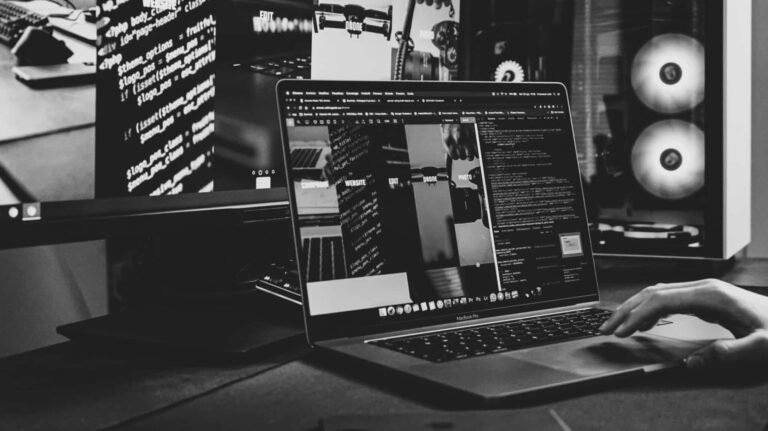 Modern workspace with a laptop and multiple screens showing a professional website setup. Photo by Francesco Lotti.