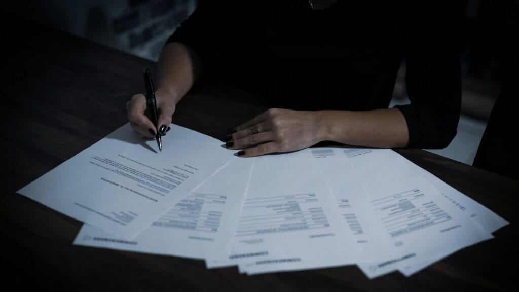 A person going through documents representing UK website legal requirements. Photo by Dimitri Kara Stelev. 