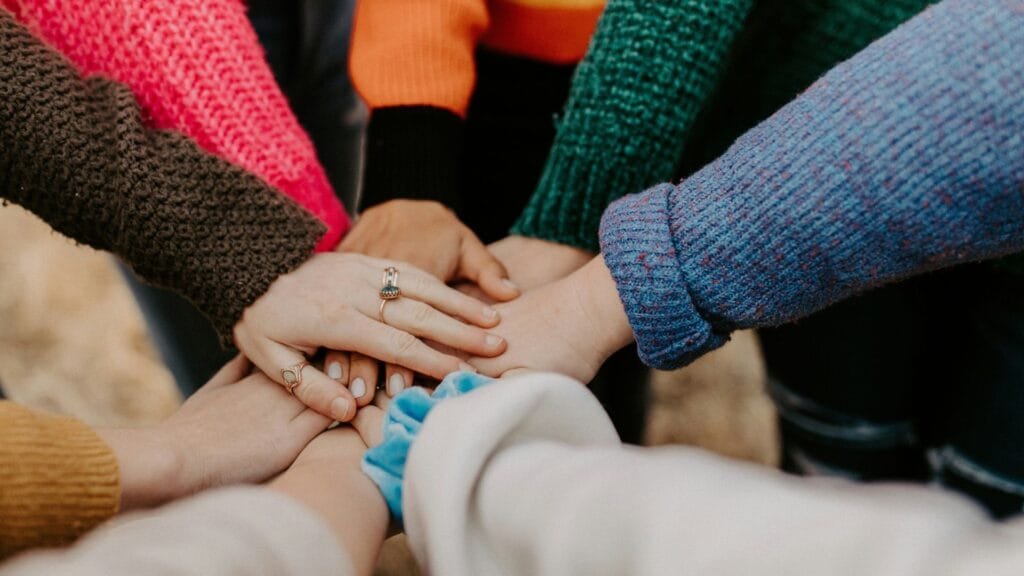 An image of lots of hands together in a circle. Photo by Hannah Busing.