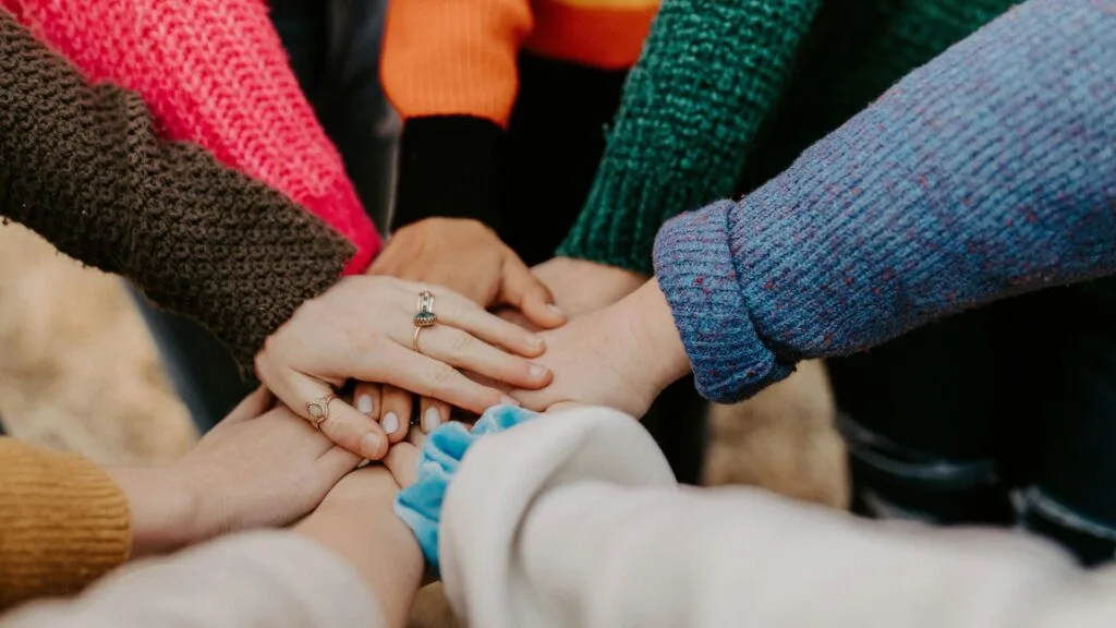 An image of lots of hands together in a circle. Photo by Hannah Busing.