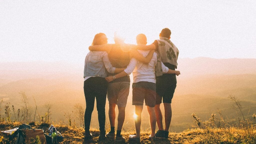 A small group of people with their arms over each others shoulders. Photo by Helena Lopes.