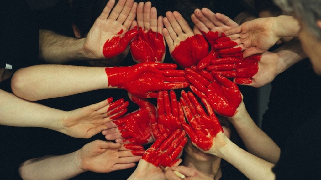 Many hands connected with a heart painted in the middle of the hands. Representing why become a community interest company. Photo by Tim Marshall.