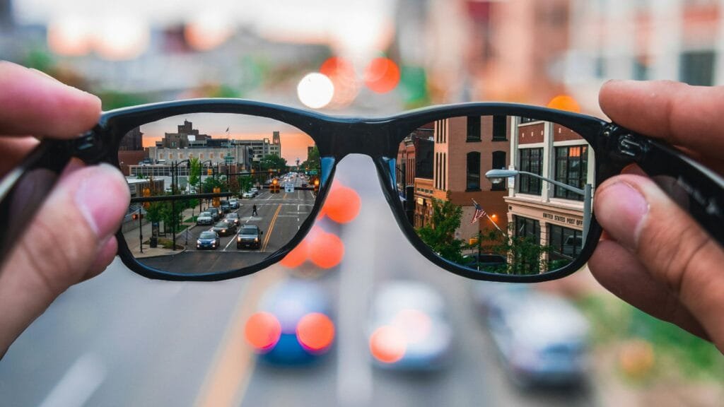 Person holding smart glasses overlooking a city to illustrate the growing role of augmented reality in everyday life. Photo by Matthew Fassnacht.